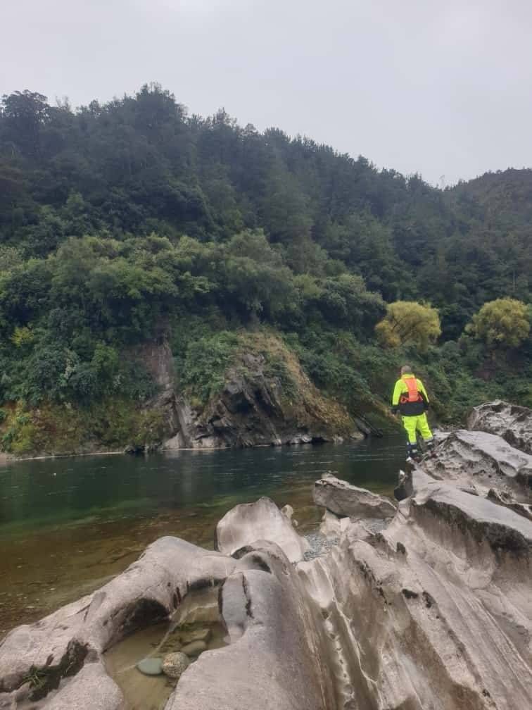 a man (sam) standing with his arms open wide infront of a large lake in new zealand Aotearoa