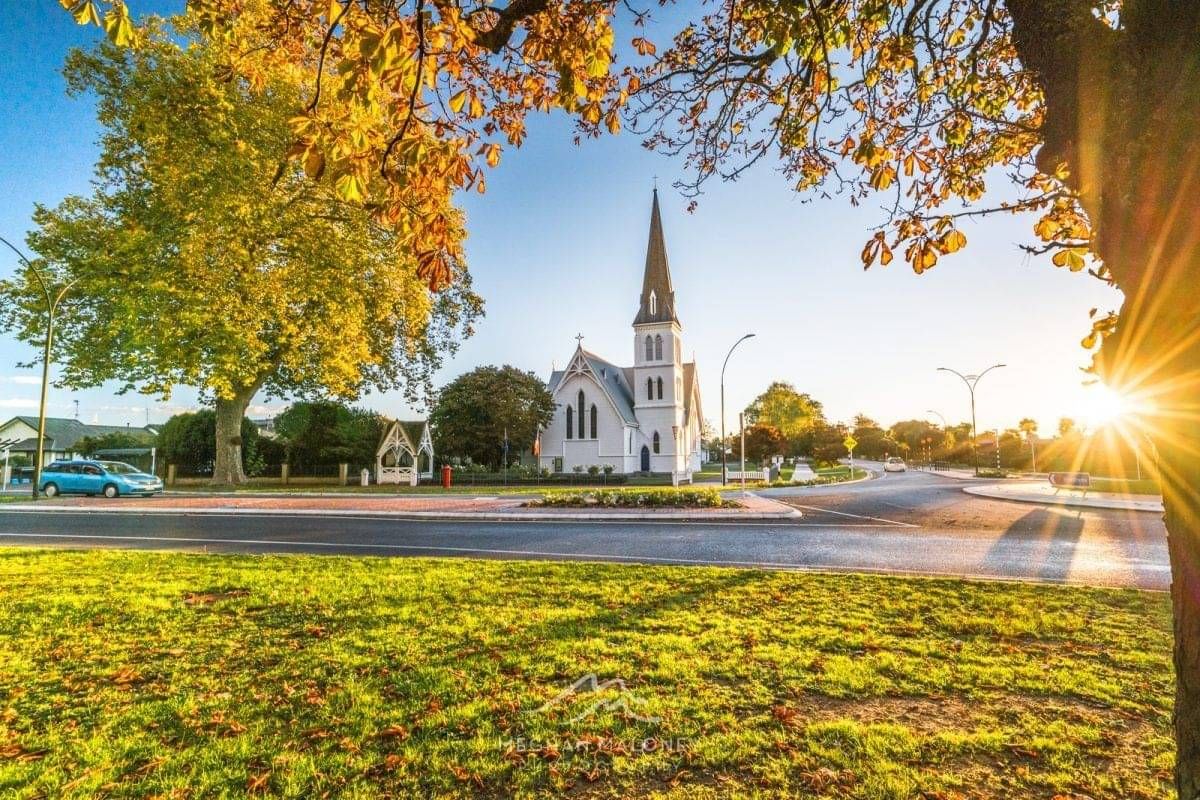 St Andrew's Church and autumn trees on a Cambridge NZ street at sunset