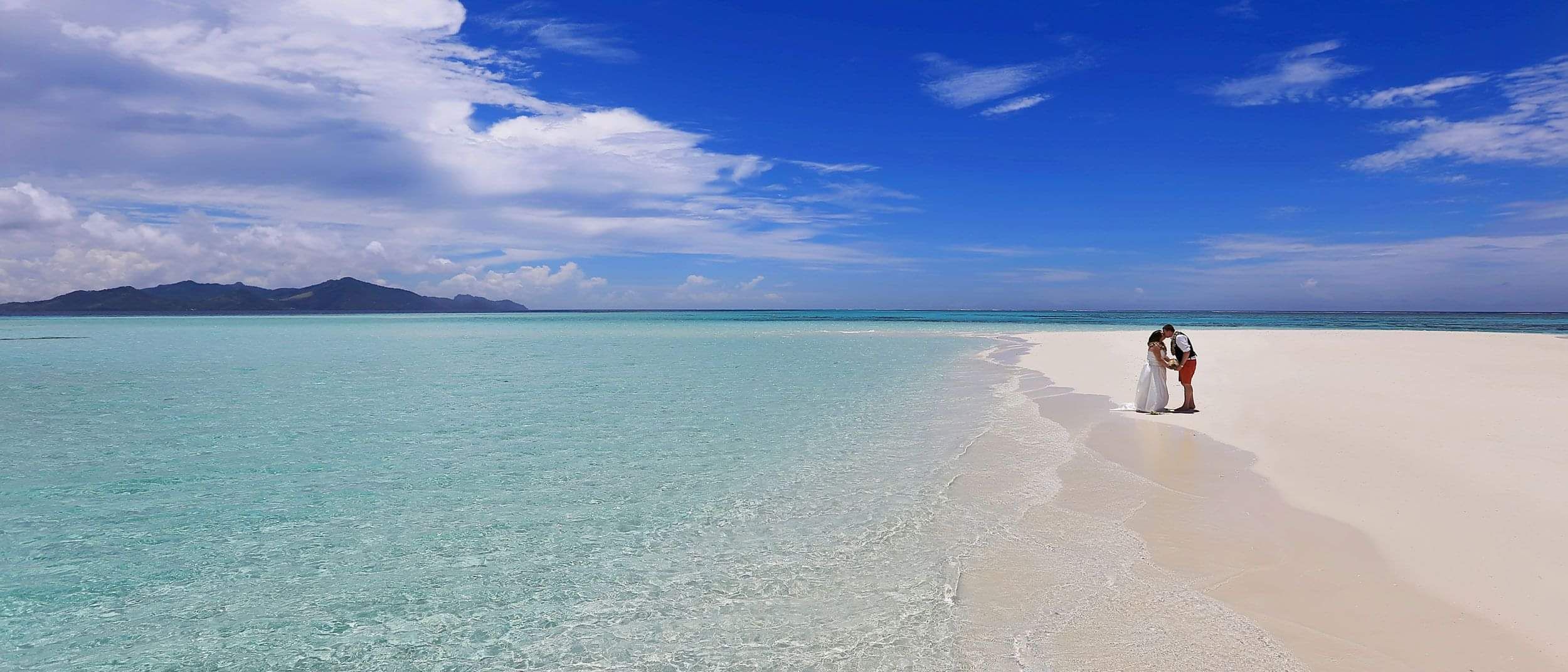 Couple standing together on a secluded tropical beach during a destination wedding