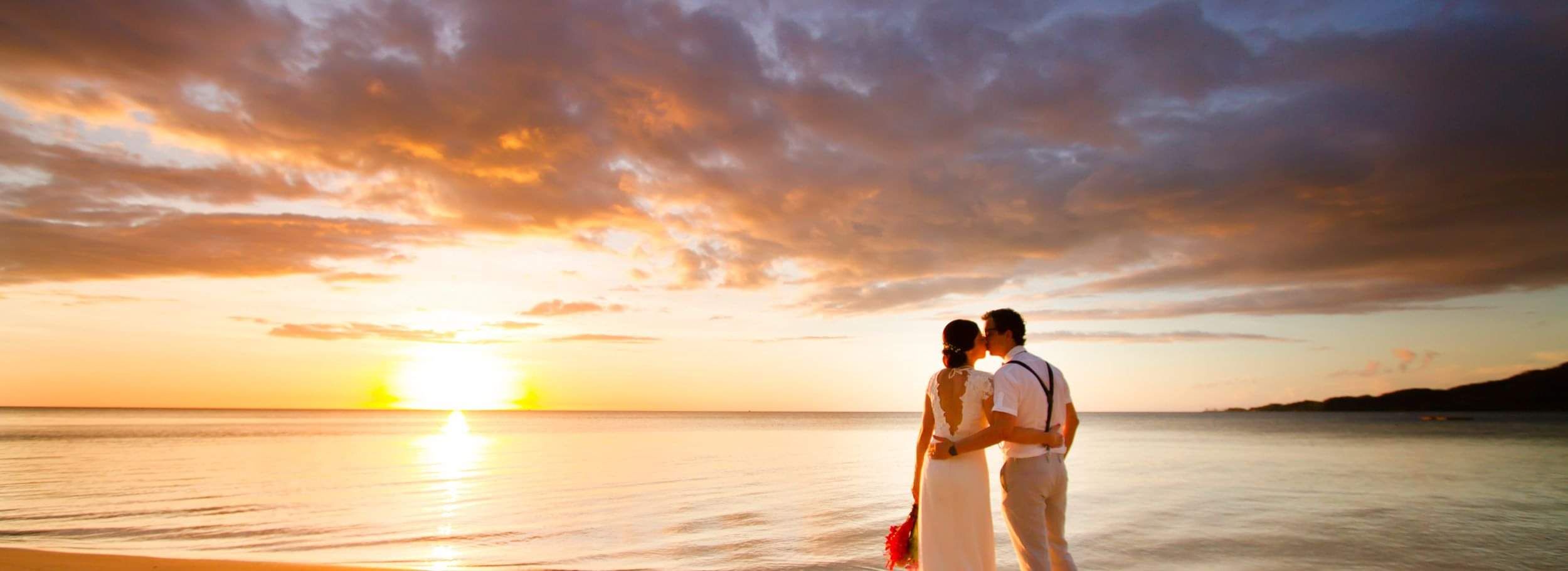 Couple in embracing on beach with ocean around them