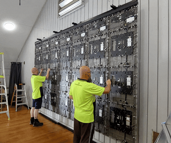 two men in high vis installing LED screen / LED screen installed with image of coral on it
