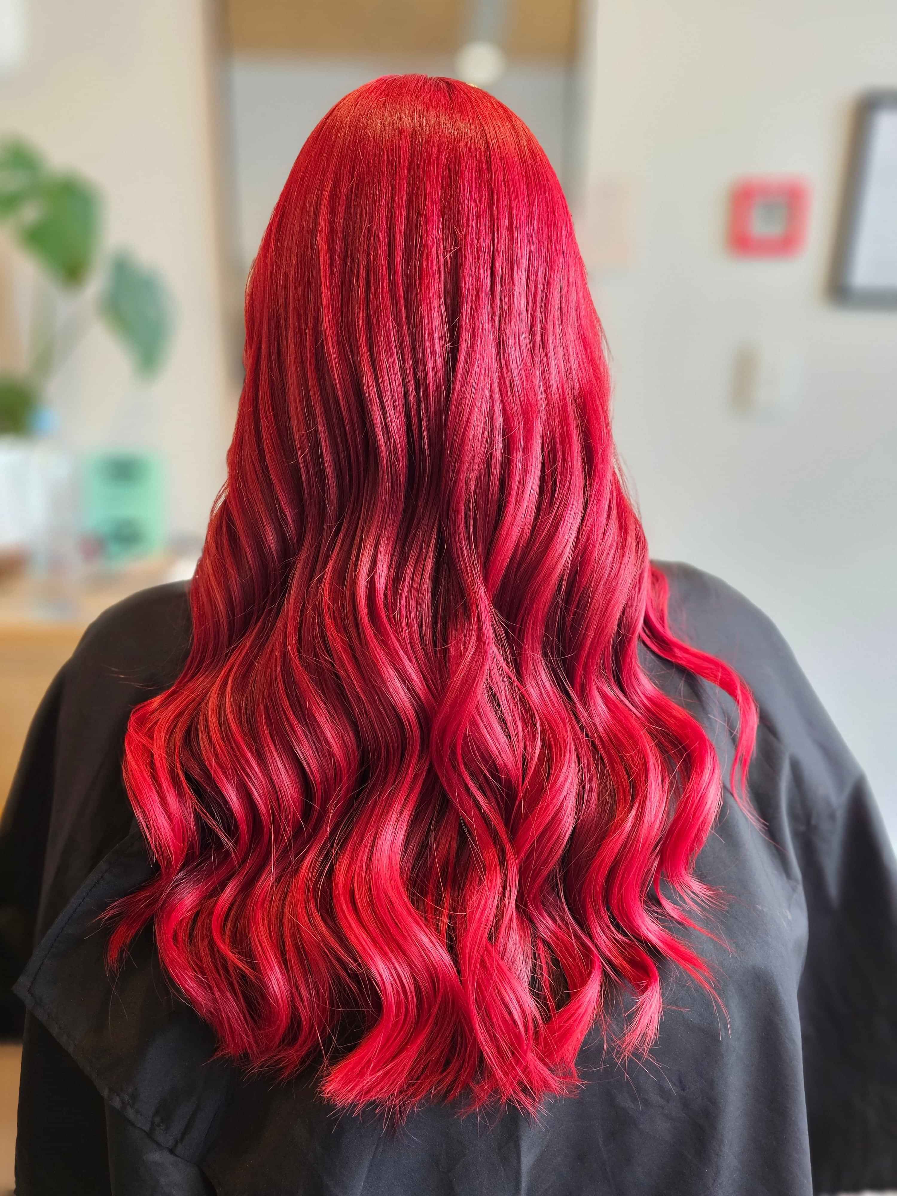 A polaroid style image of a bright red/pink hair colour created by Hair by Shiyee.