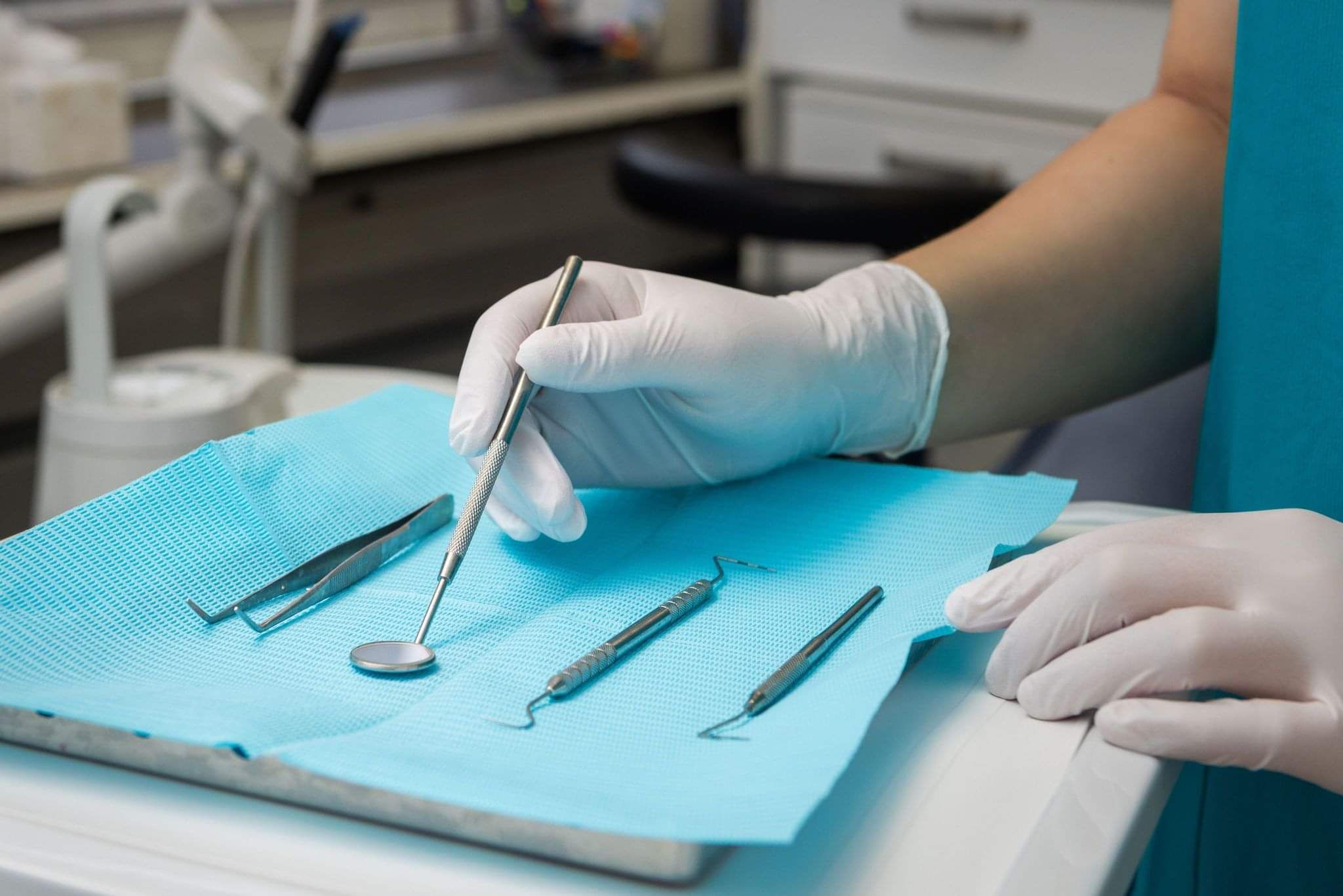 Hands with gloves holding dental tool