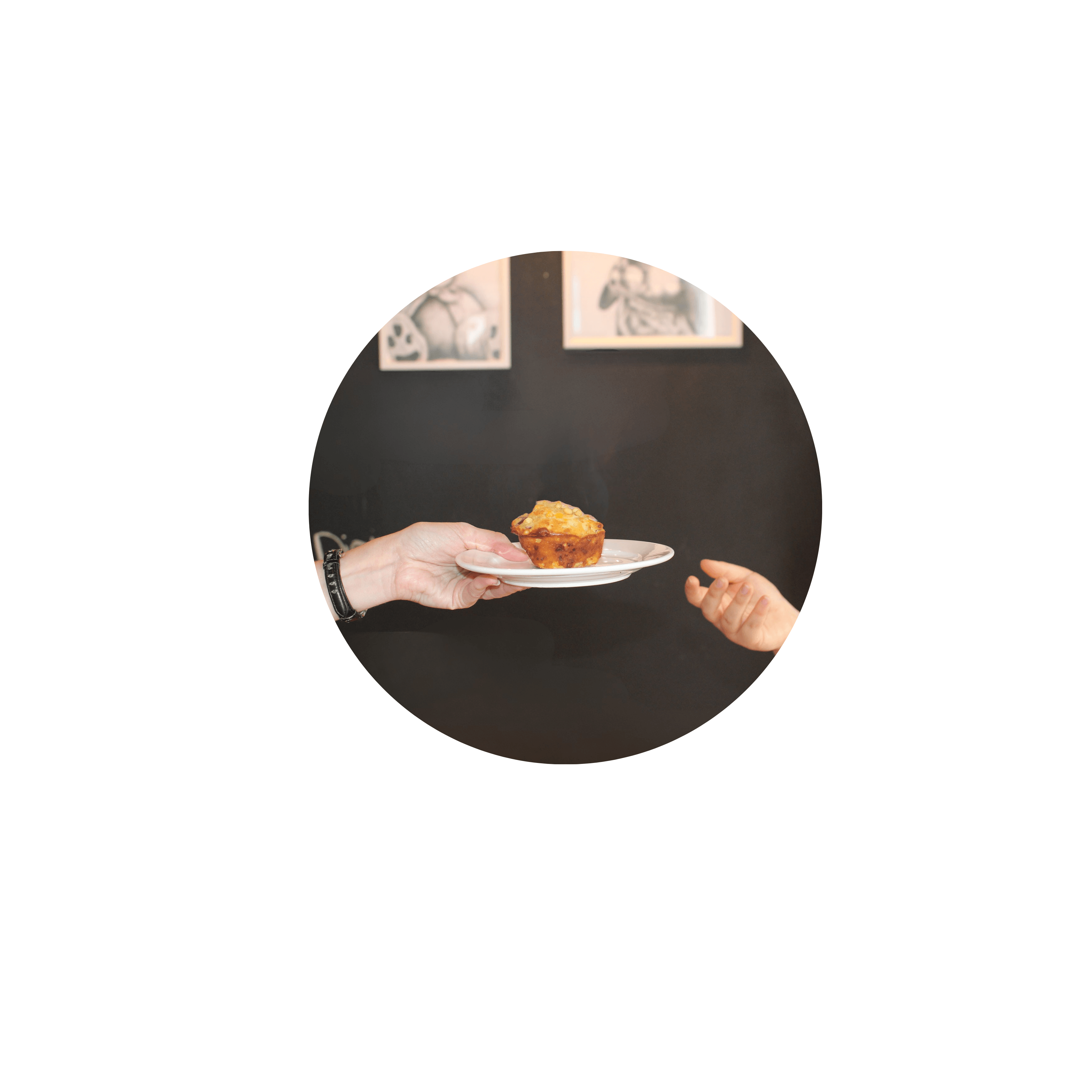 A close up shot of someone handing a plate with a muffin to another person.
