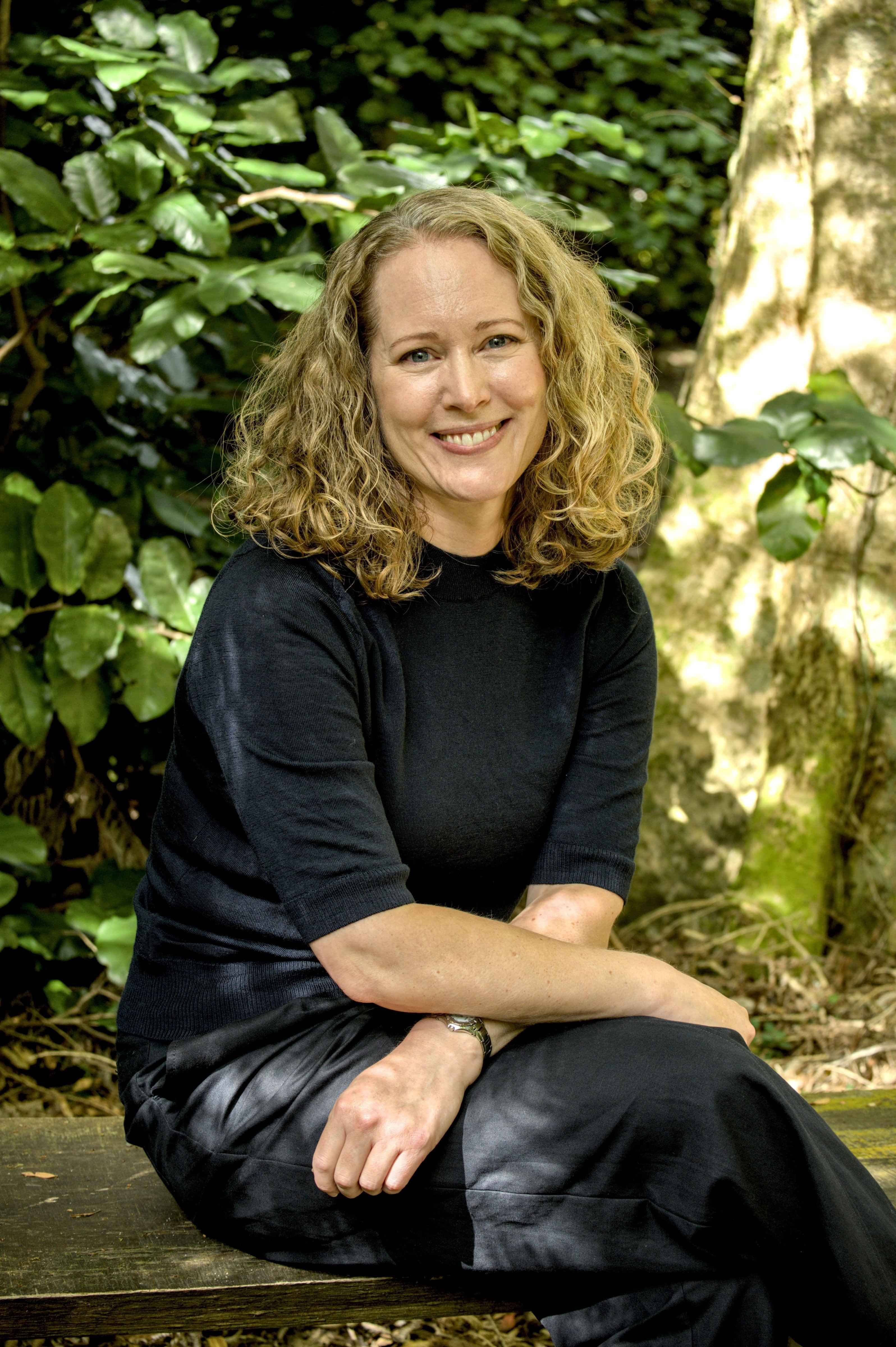 Smiling woman sitting on a bench in a forest in Wellington, New Zealand