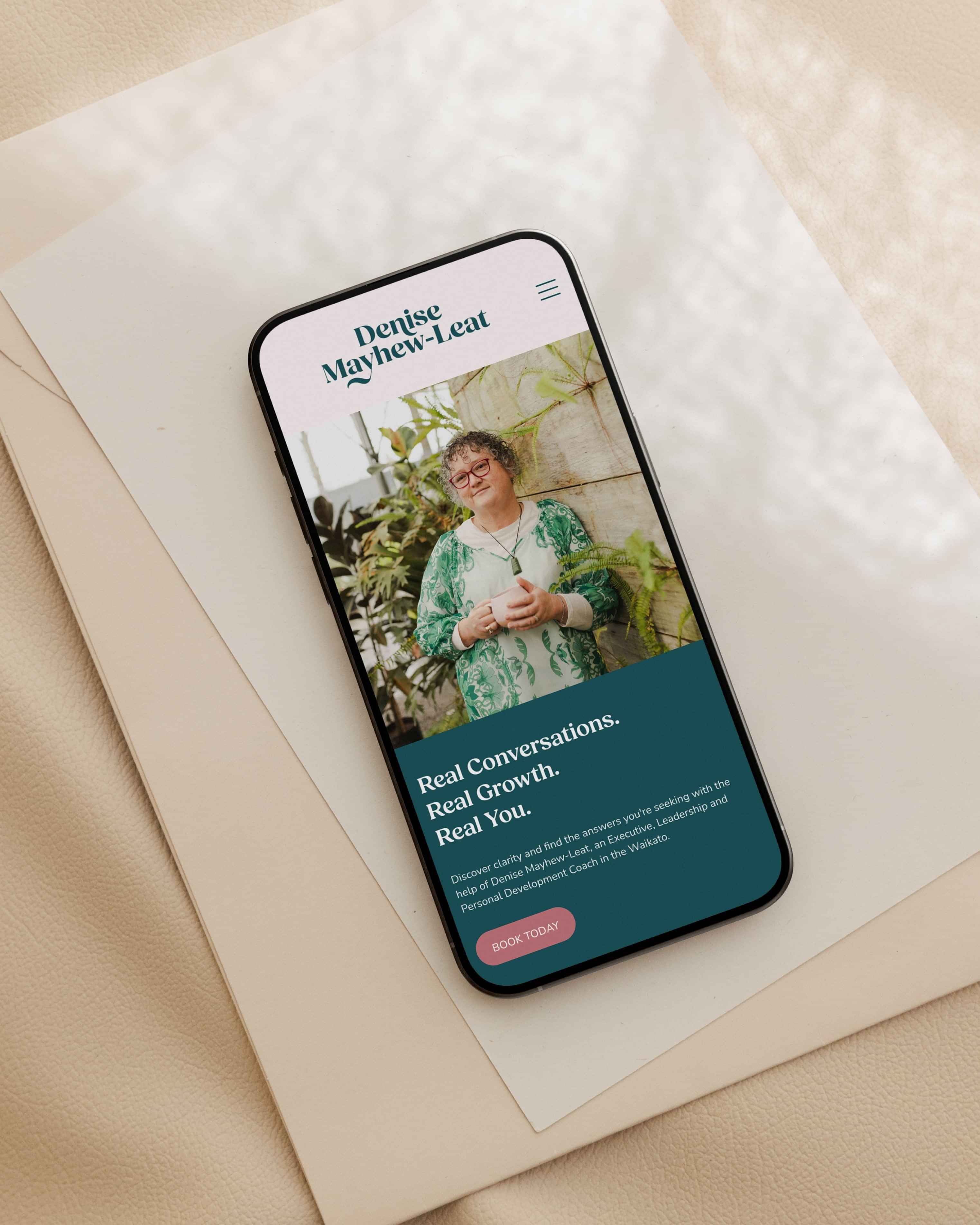 Image of iPhone mockup with Denise Mayhew-Leat’s website. By Creative Box