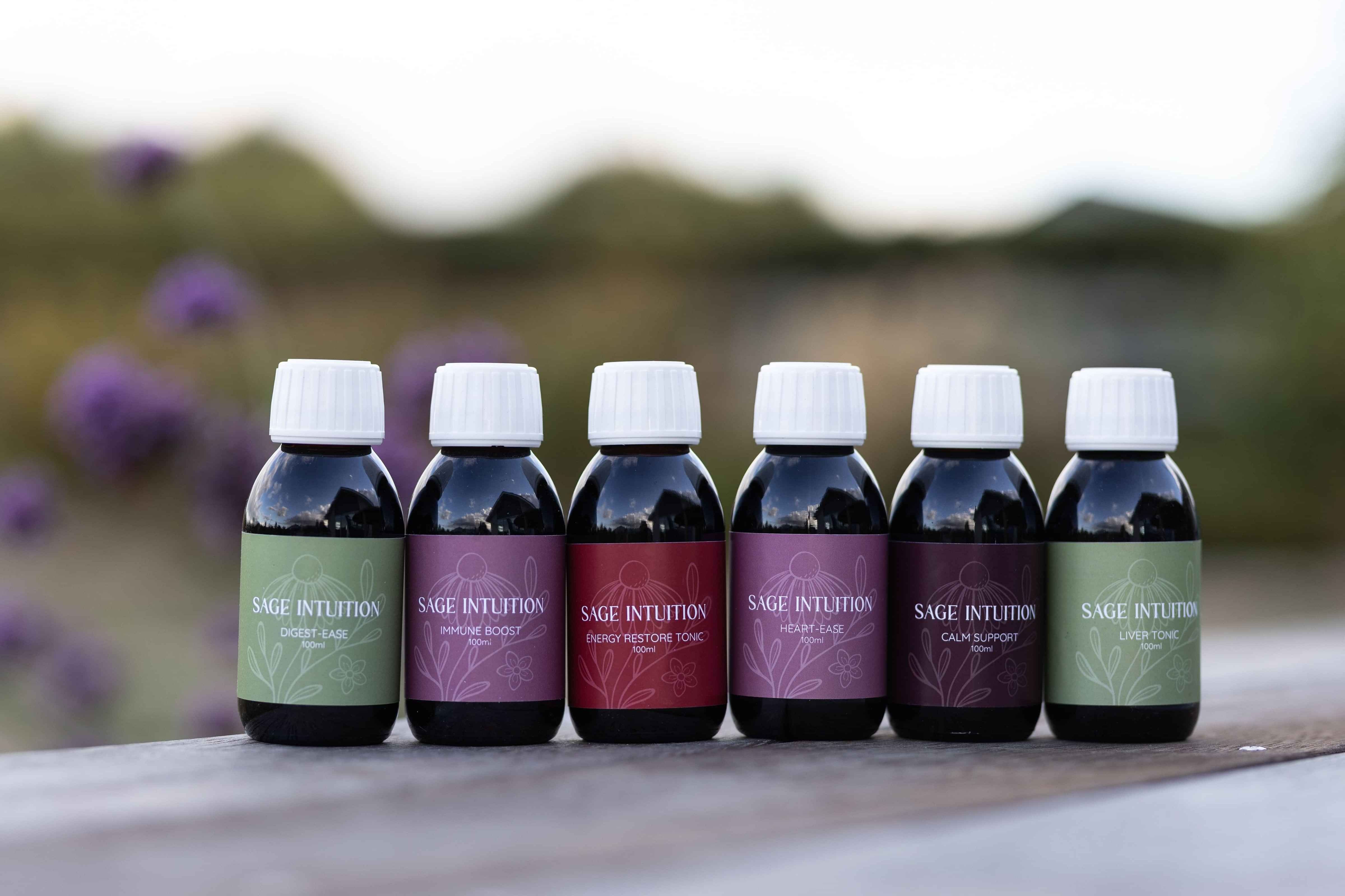 Image of six herbal medicine bottles with floral colourful labels printed on them by Sage Intuition. Photo by Holly Horforth. Waikato, NZ. 