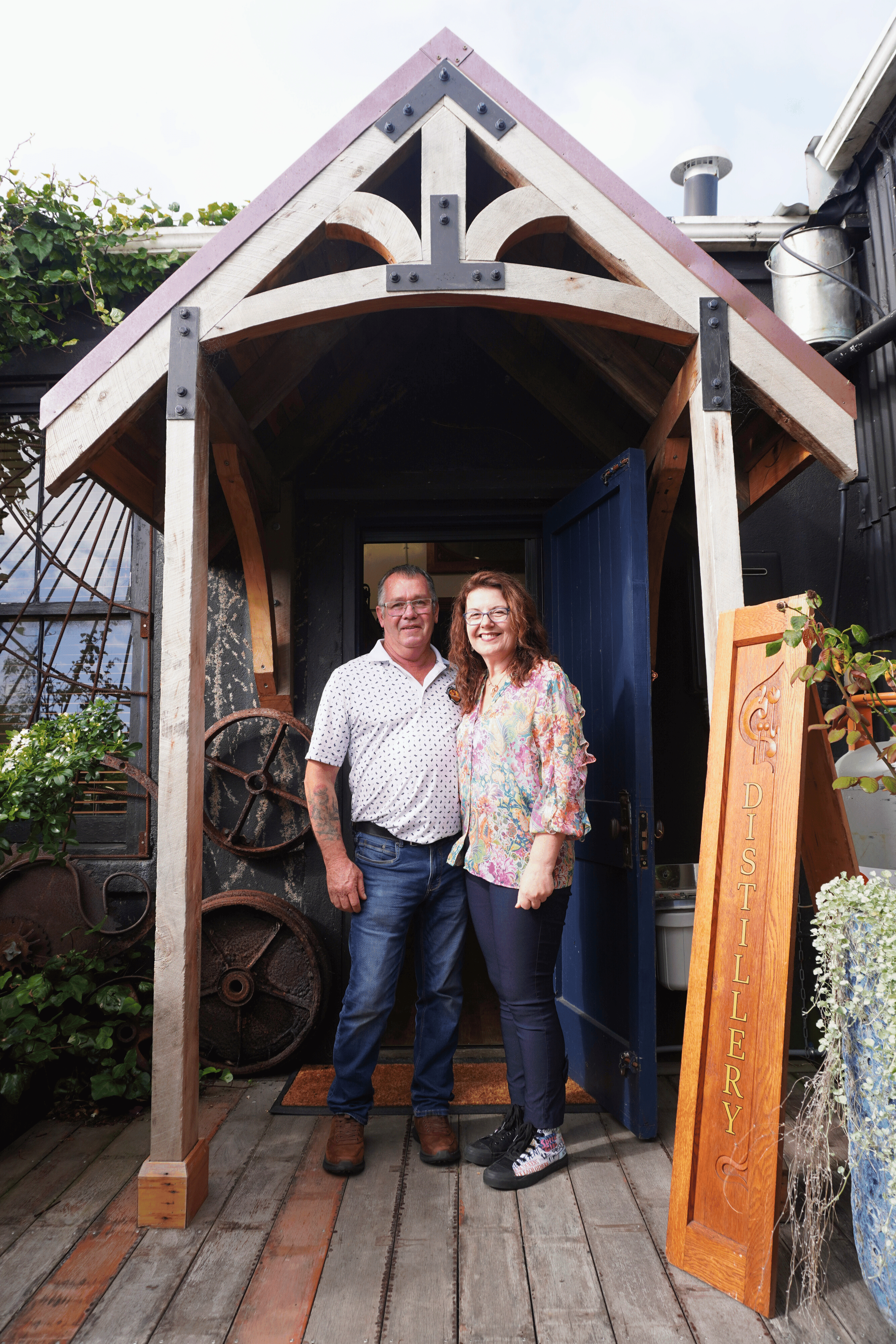 Shawn and Rhonda smiling standing next to some gin distilling equitment.