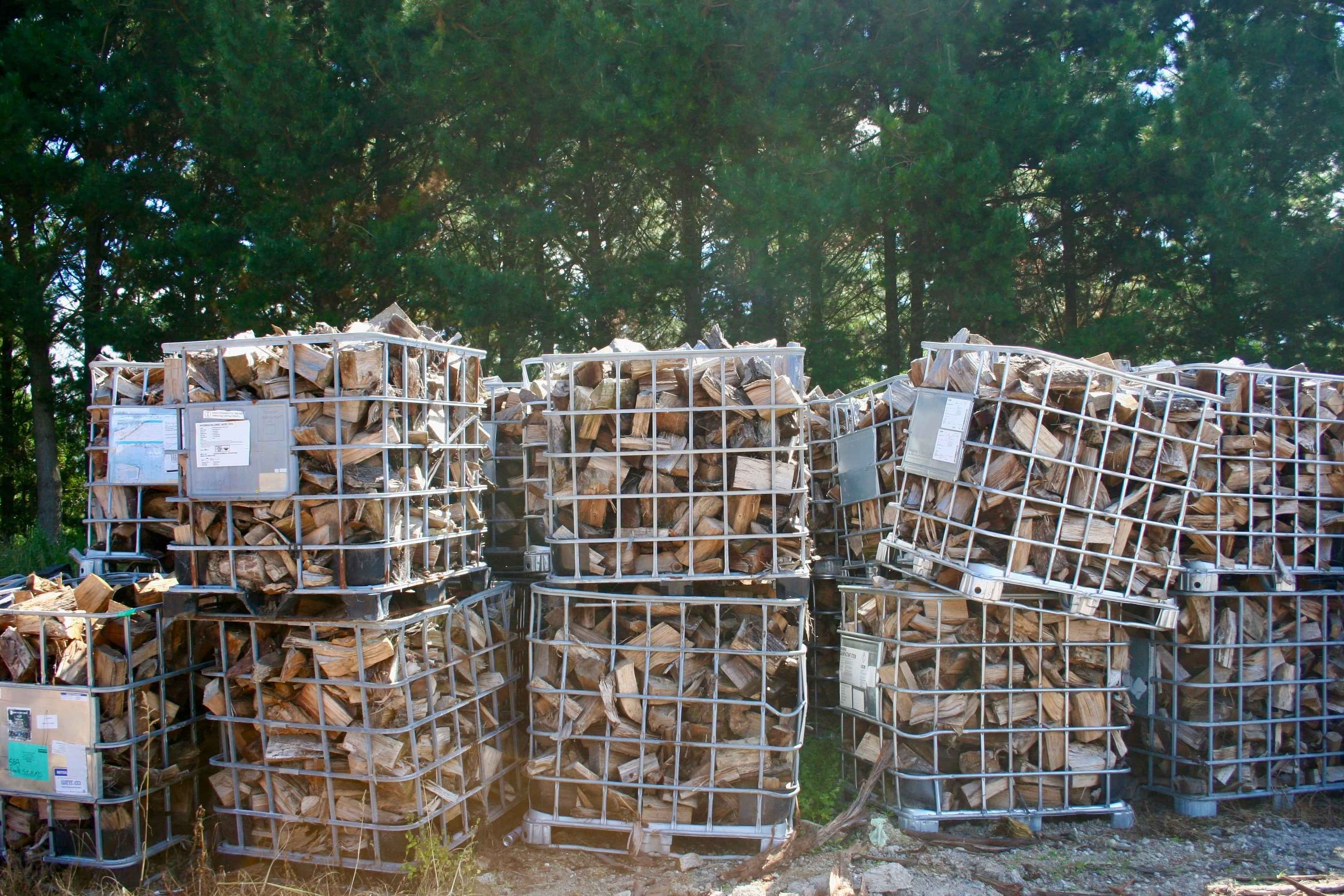 Photo of firewood stored in crates with a view of the forest behind them