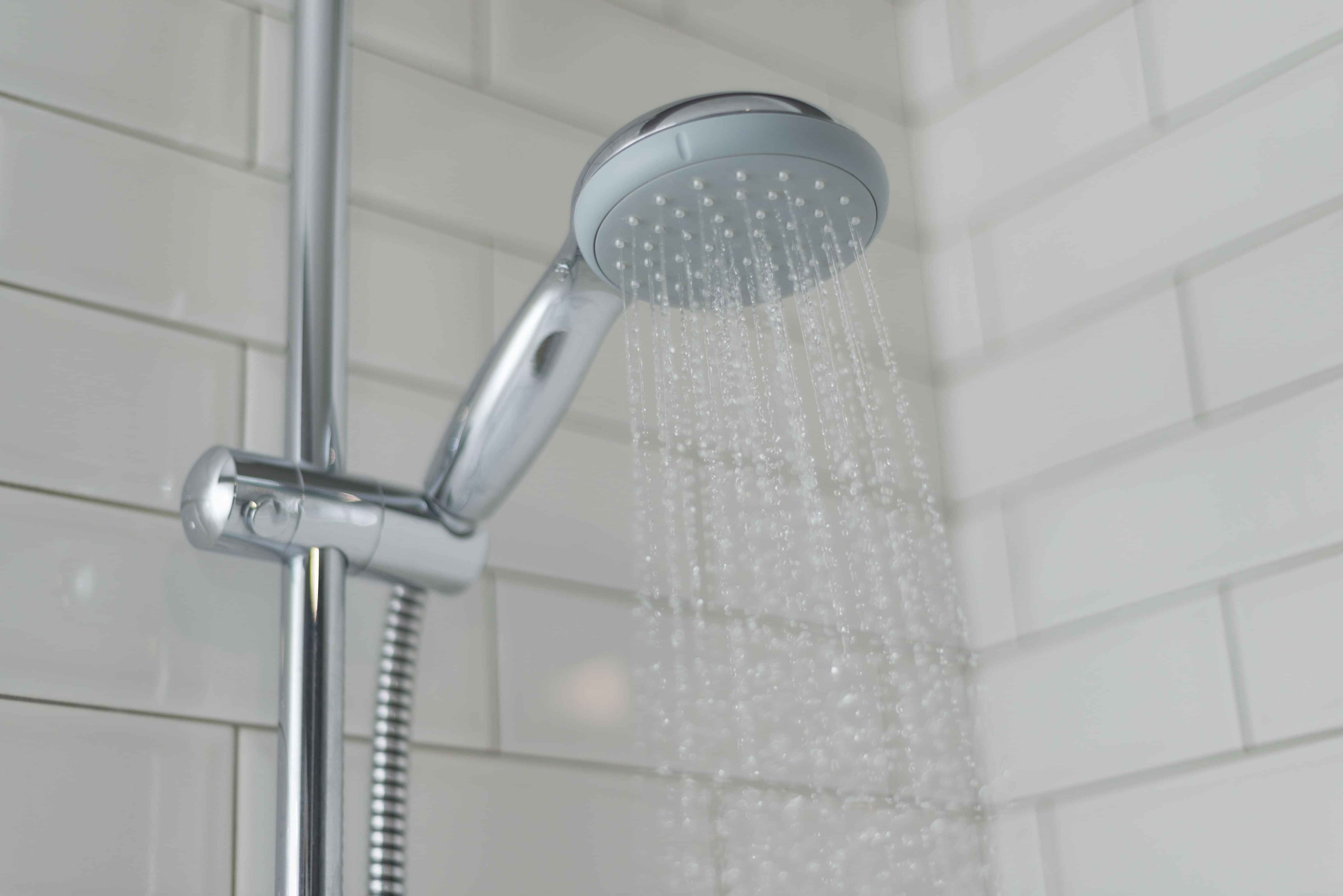 A running shower head in a tiled shower.