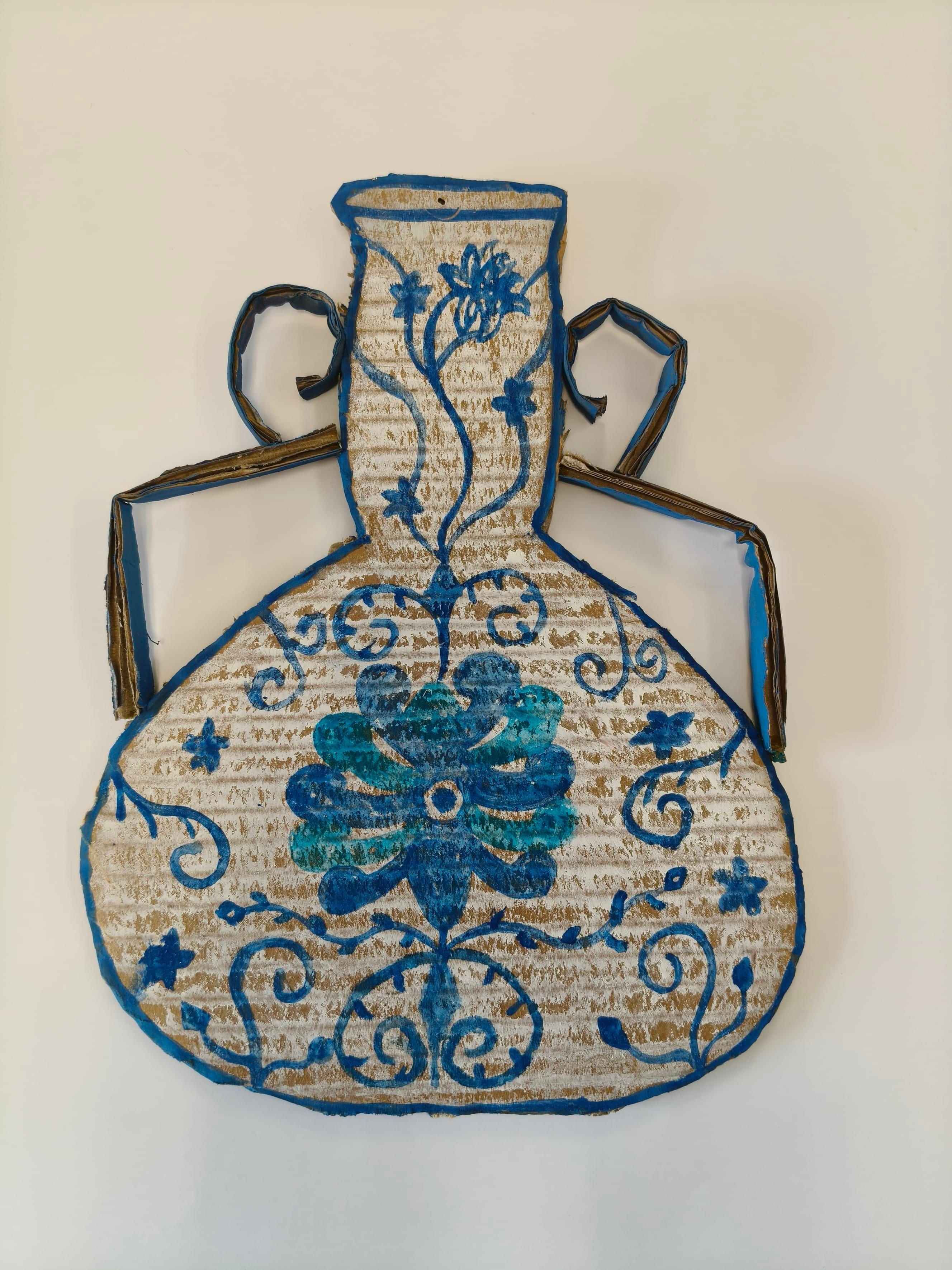 An artwork of an ornated vase cut out of cardboard and decorated with blue flowers.