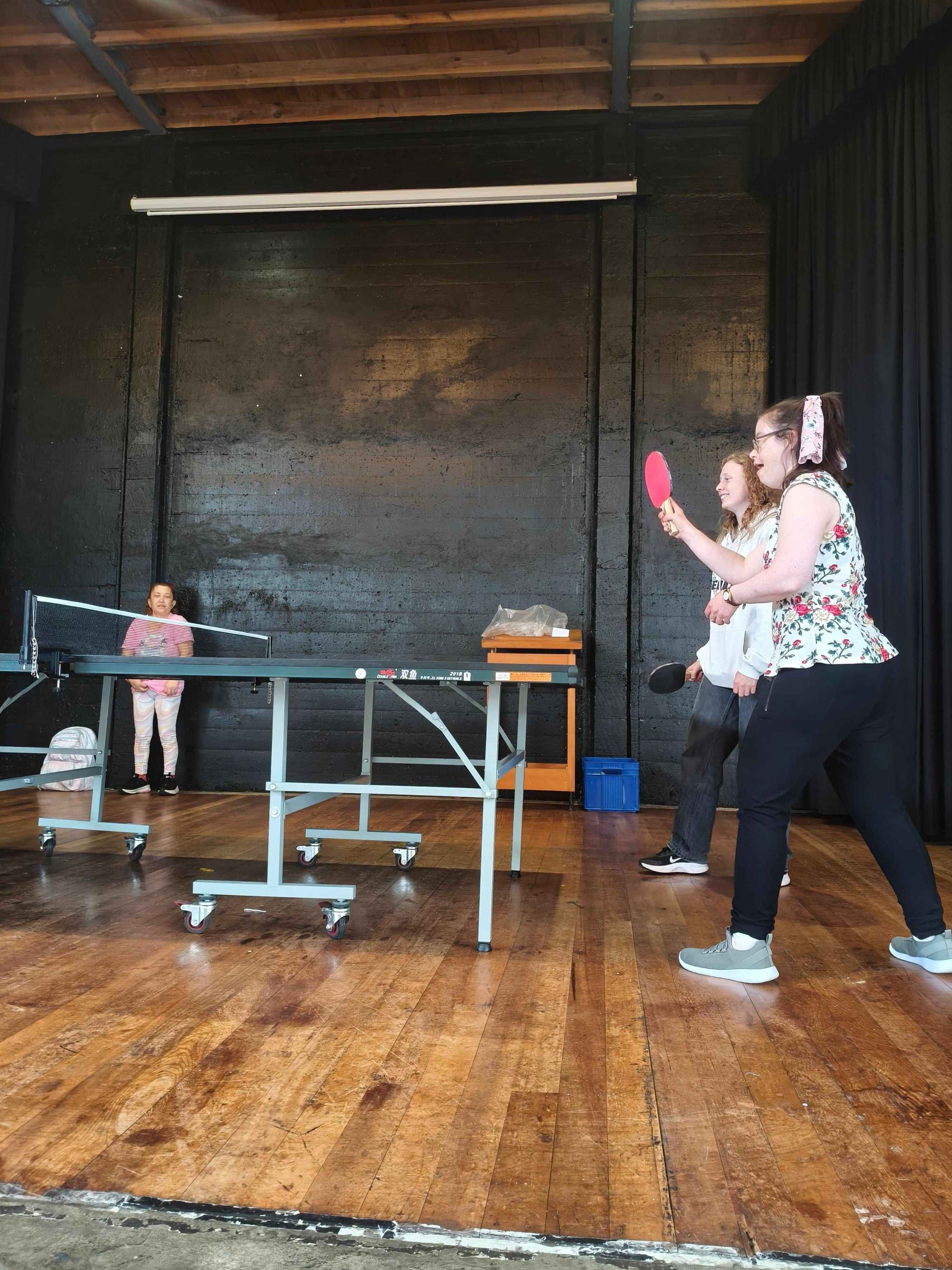 Two ladies having fun playing table tennis.