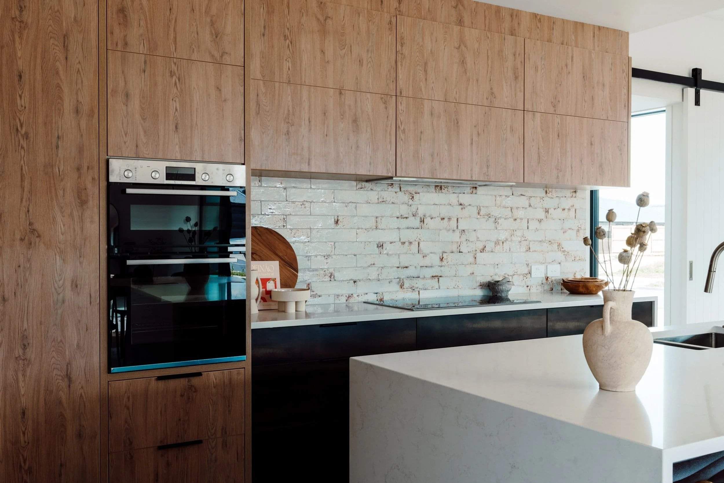 Modern kitchen with rustic brick splashback and wooden cupboarding