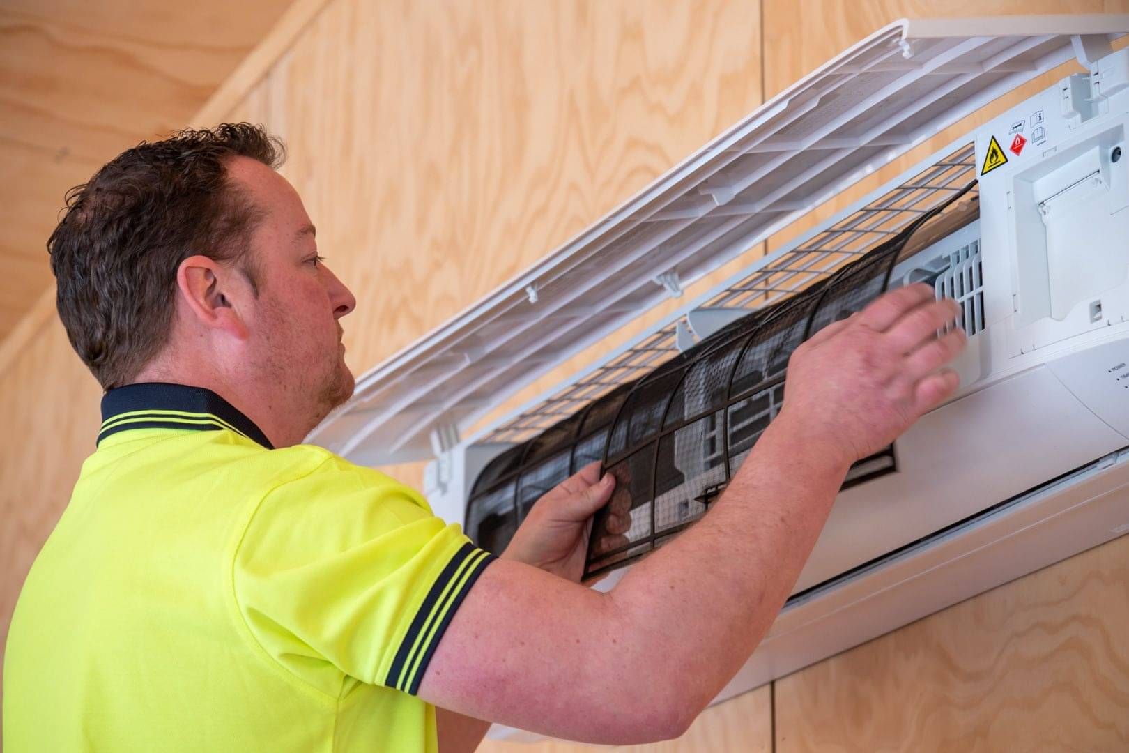 Temprite technician cleaning the filter on a wall-mounted heat pump