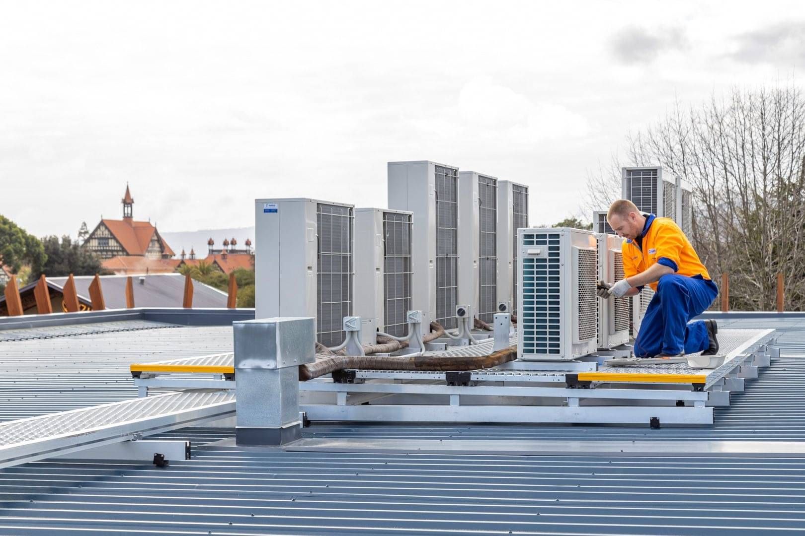 Technician installing multiple rooftop commercial air conditioning units