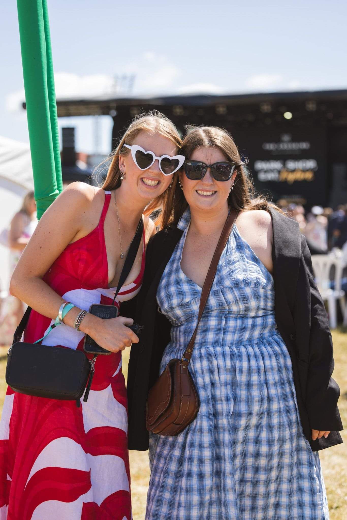Two ladies with sunglasses smiling on a bright sunny day