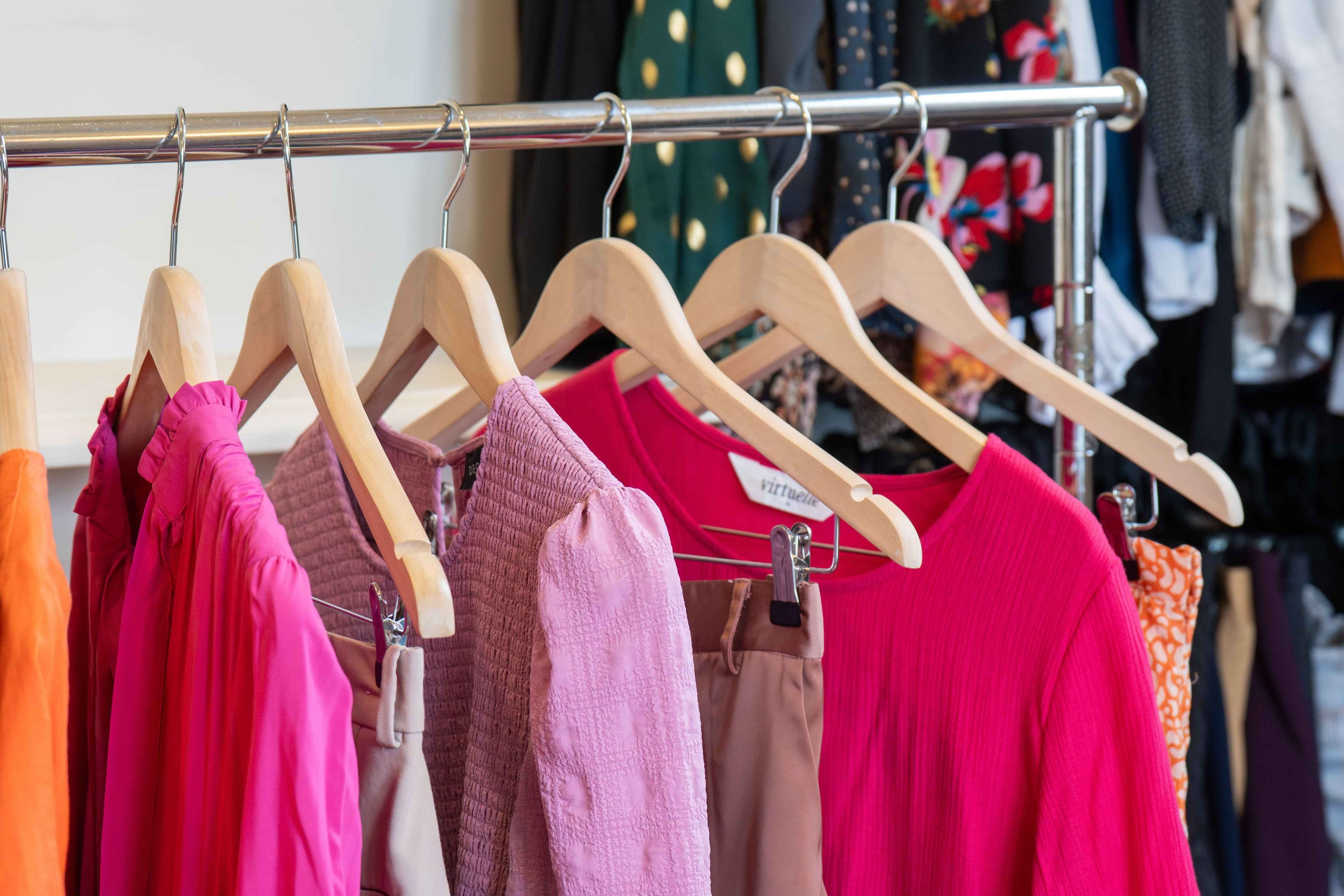 Dress for Success Christchurch colourful women's clothes on a portable silver coat rack with wooden clothes hangers.