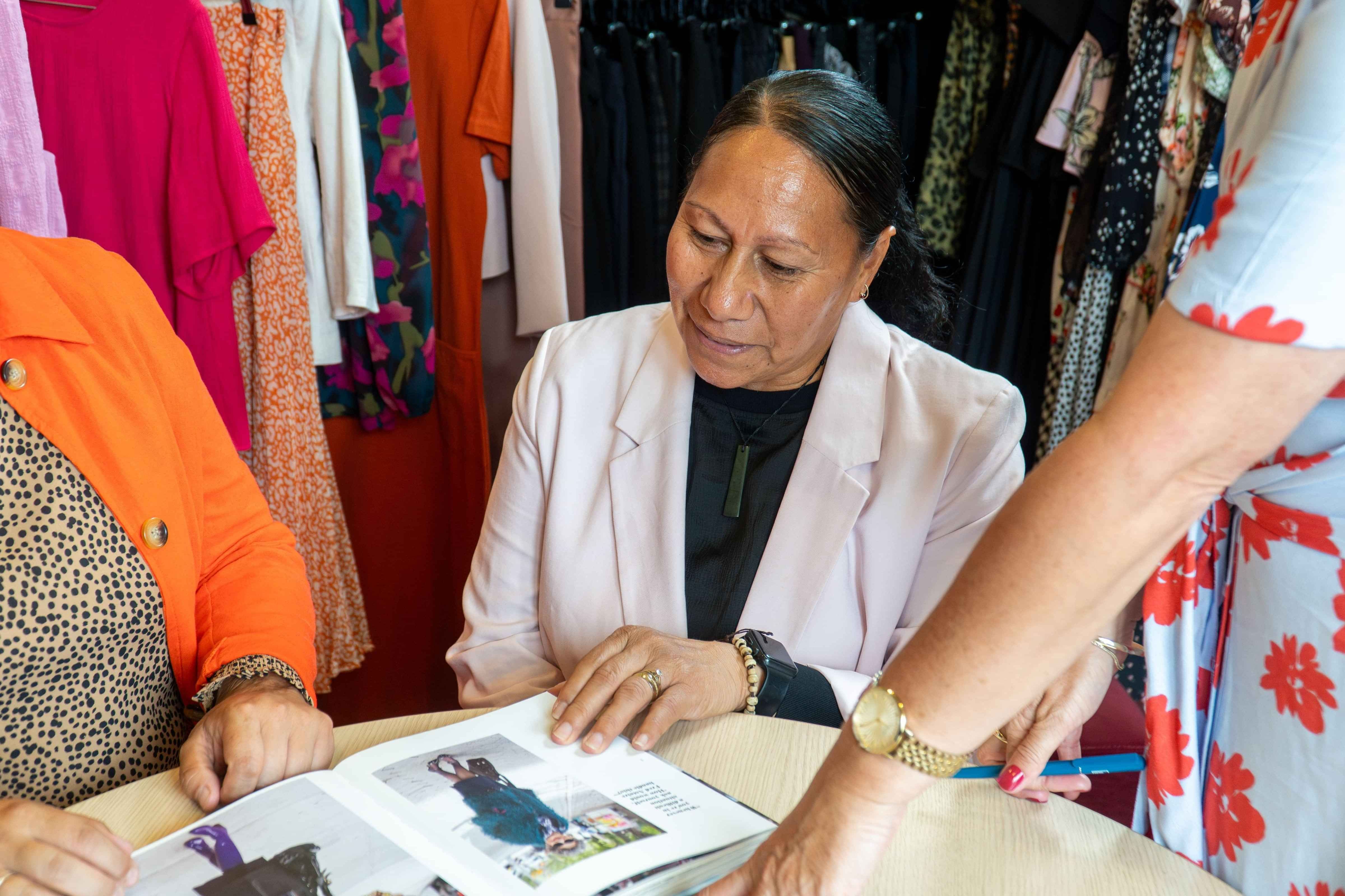 Dress for Success client looking through a fashion inspiration book with staff member
