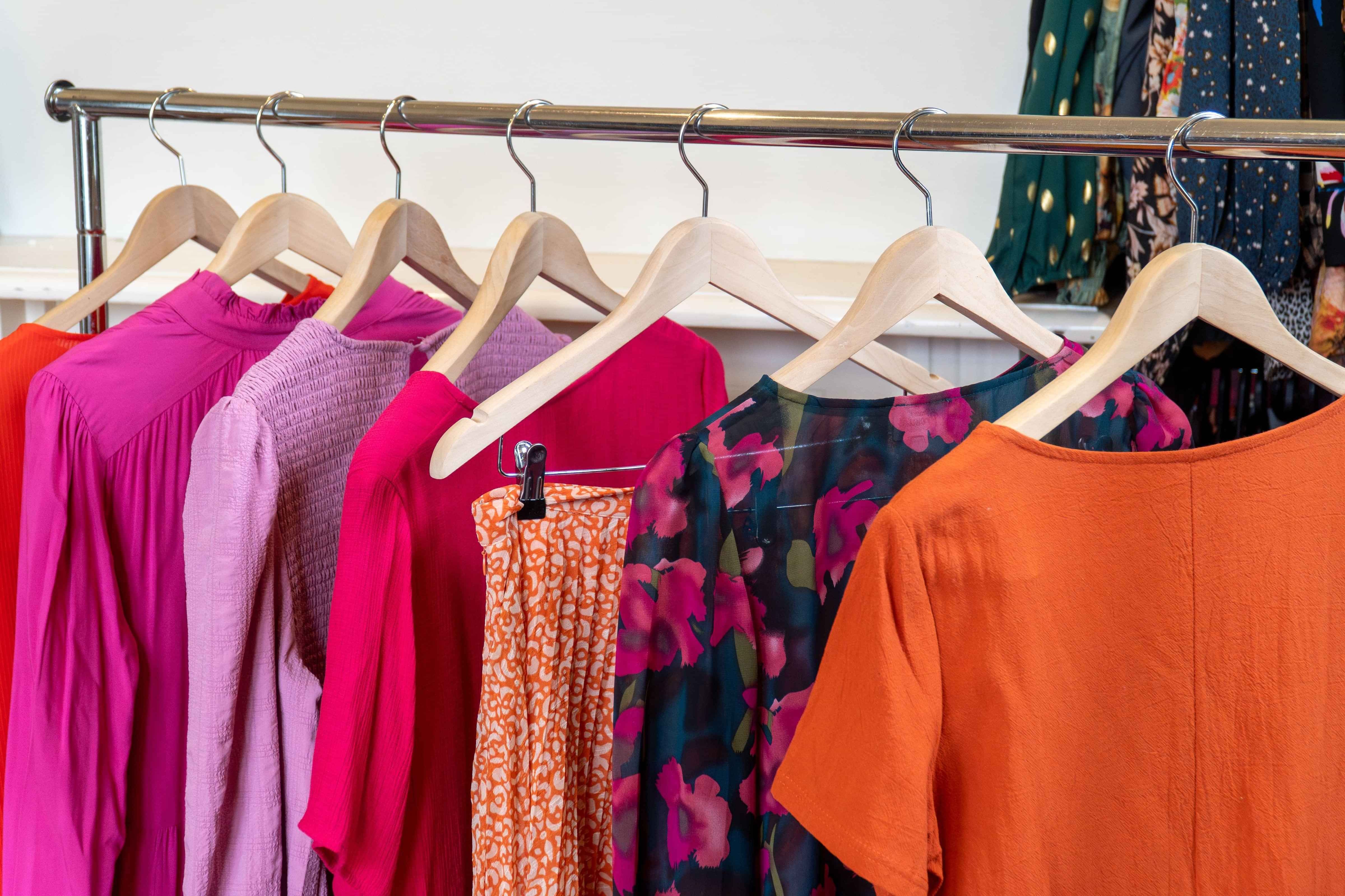 Variety of different colourful clothing items hanging on a portable coat rack