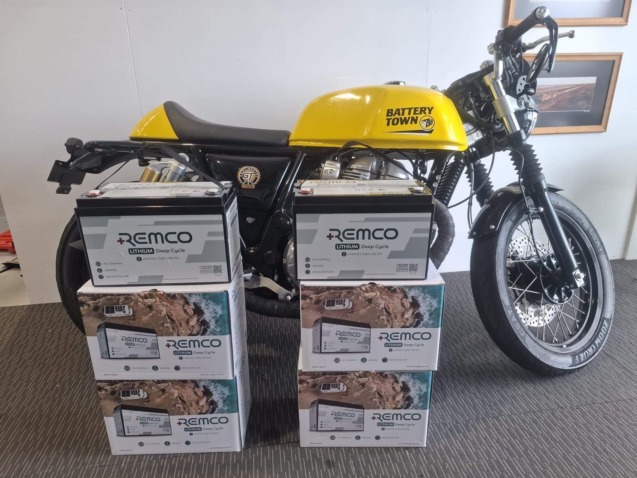 A Battery Town branded vintage motorbike with two stacks of Remco batteries in front.
