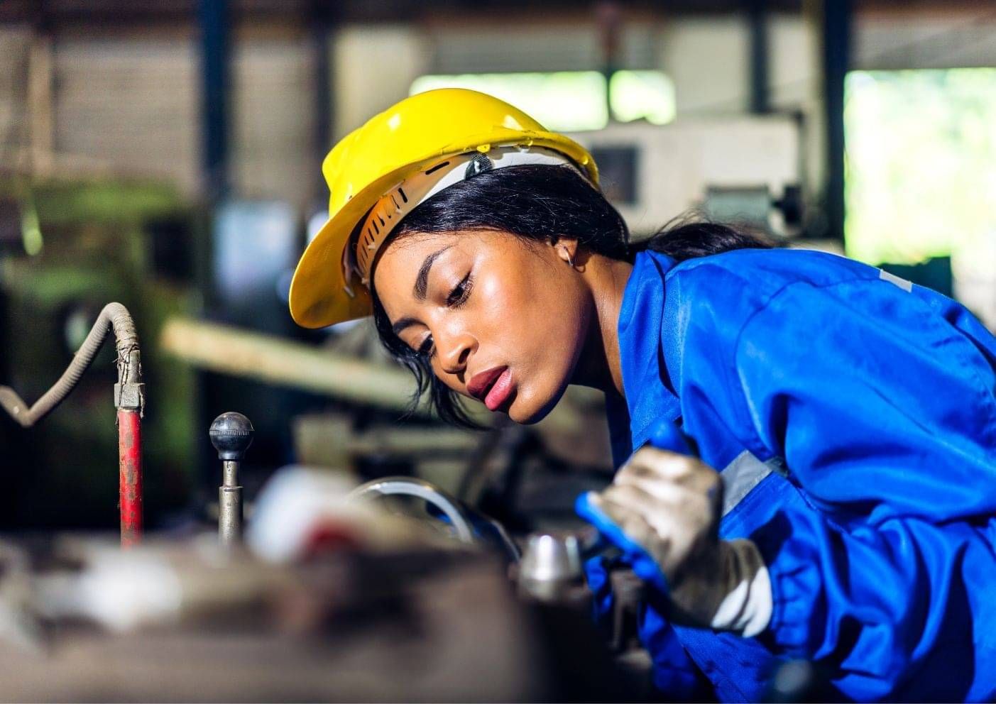 Worker in a hard hat and high-vis inspecting industrial machinery