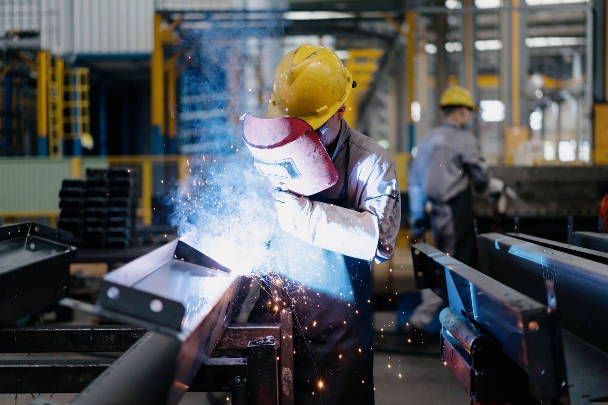 Welder working on a metal fabrication in a manufacturing workshop