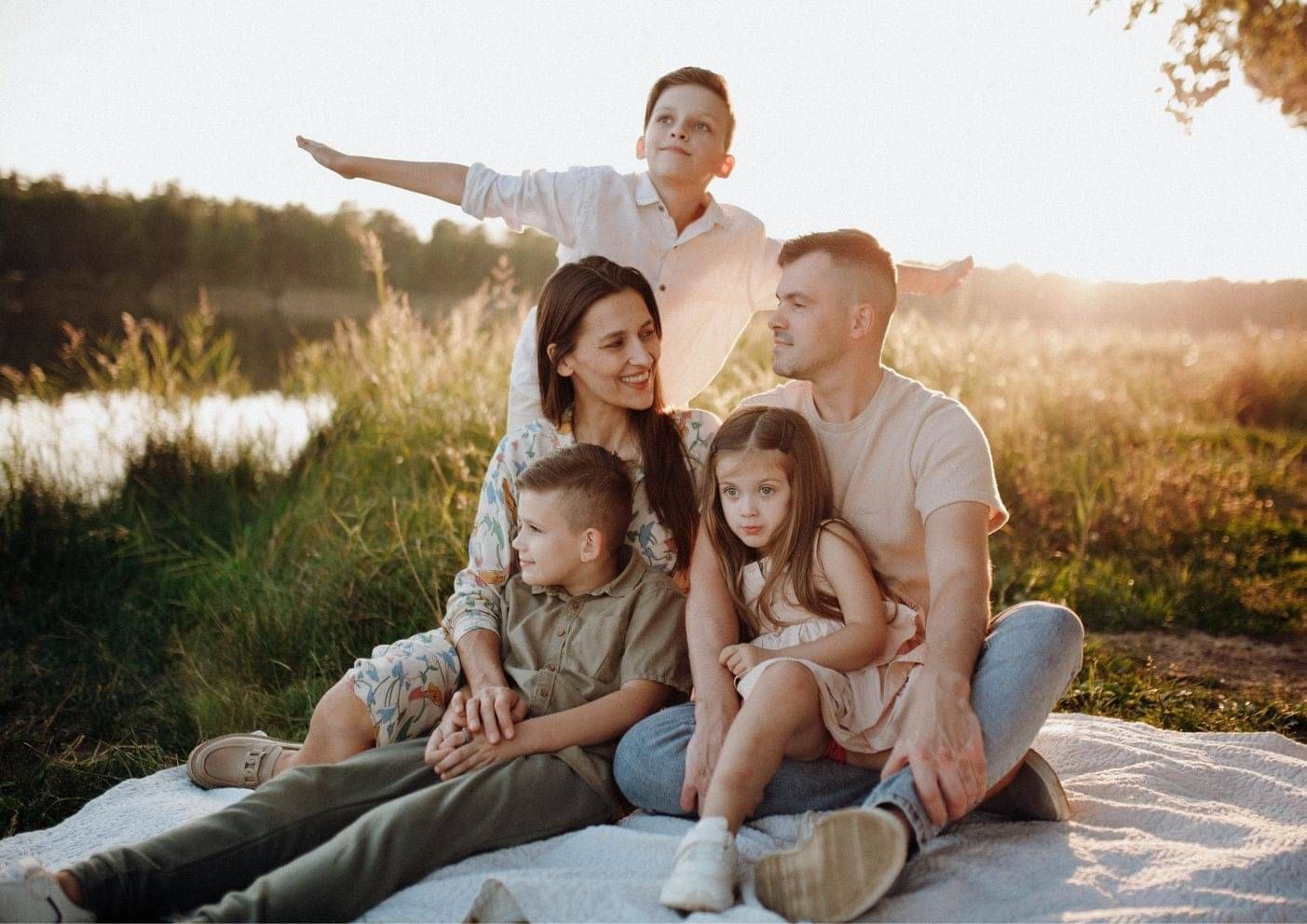 Father pointing out the view to his family in a field at sunset, settled in New Zealand
