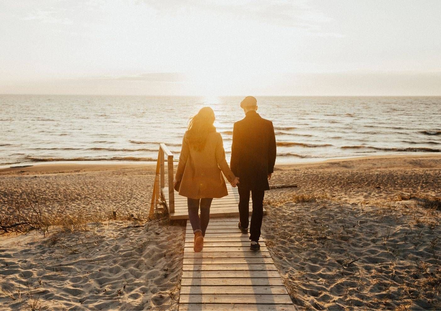 Couple walking together on a New Zealand beach at sunset