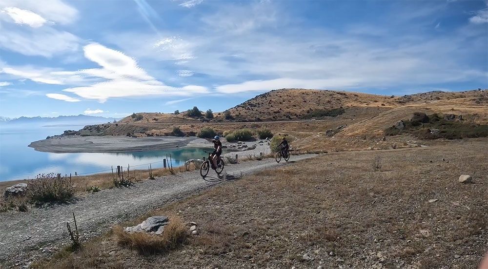 Pointing at the lake while riding the Alps 2 Ocean · classic 7 day tour