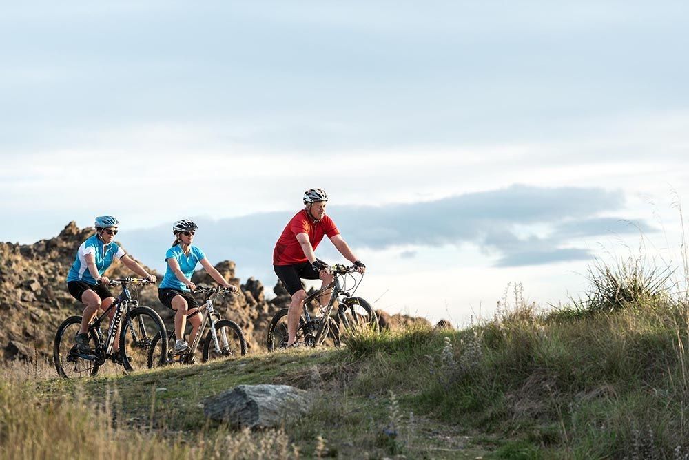 Three riders going up a hill along the Otago Central Rail Trail