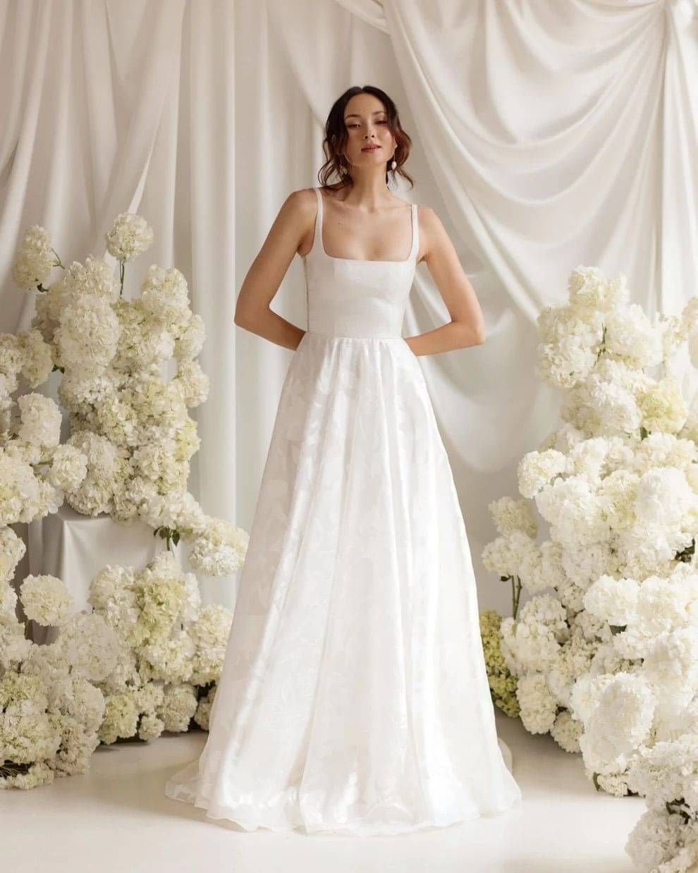 Bride wearing LUMI wedding dress amongst lots of flowers