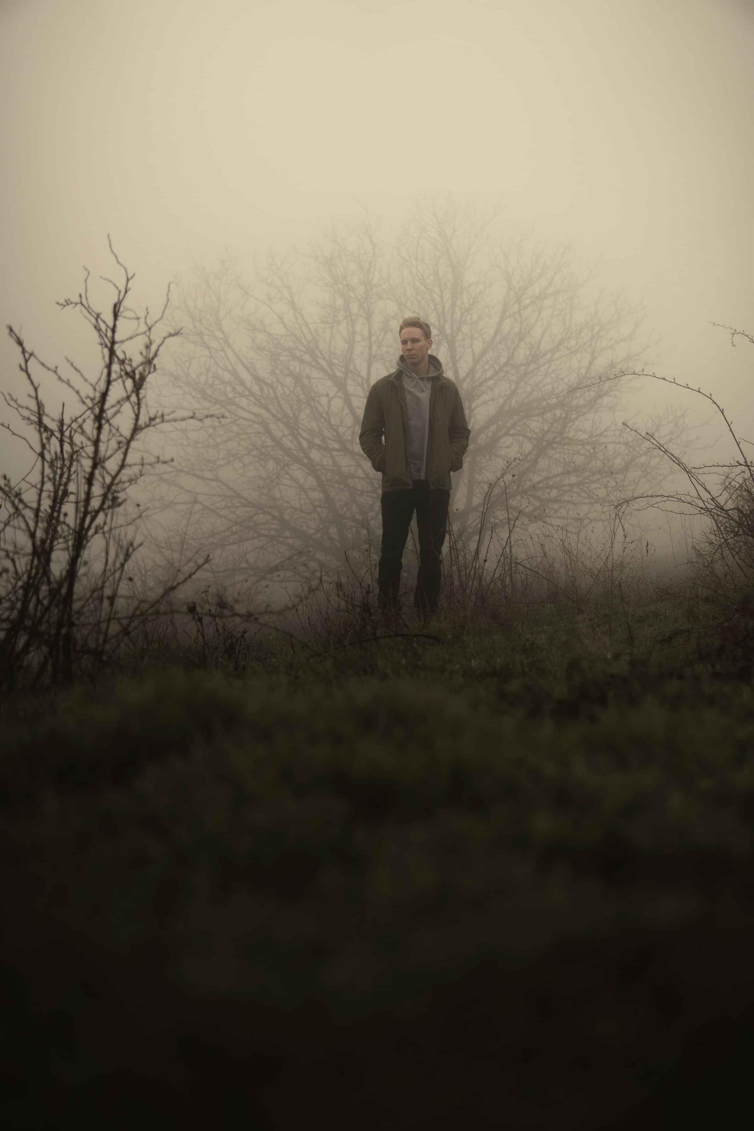 A man standing alone in a misty field