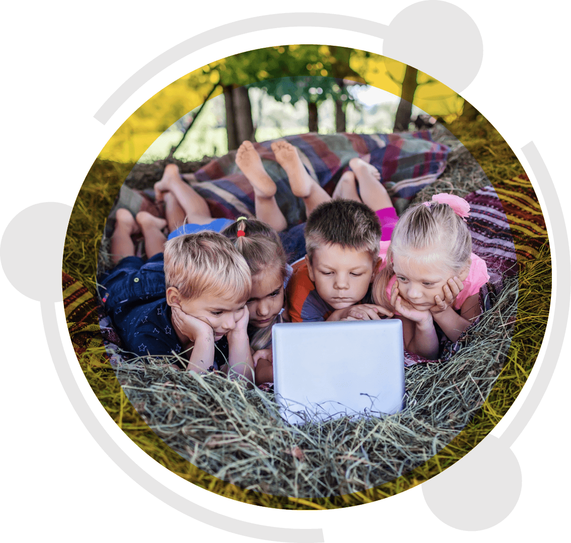 Four kids lying on a blanket in the hay watching a laptop outdoors, streaming on an unlimited rural broadband plan with no contract